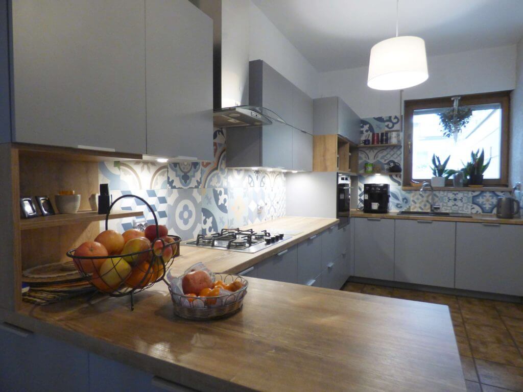 Przedstawiamy elegancką i funkcjonalną kuchnię na wymiar od firmy Aksent, która łączy nowoczesny design z praktycznością. Nasza oferta skupia się na tworzeniu przestrzeni kuchennych, które są równocześnie piękne i wygodne w codziennym użytkowaniu. Kuchnia, którą proponujemy, charakteryzuje się minimalistycznymi, szarymi frontami, które doskonale komponują się z ciepłym odcieniem drewnianego blatu. Ta kombinacja kolorystyczna wprowadza do pomieszczenia harmonię i stwarza przytulną atmosferę. Zapraszamy do kontaktu z naszymi projektantami, aby dowiedzieć się więcej o ofercie i rozpocząć projektowanie swojej wymarzonej kuchni razem z Aksent. Oferujemy kompleksowe wsparcie na każdym etapie – od koncepcji po realizację.